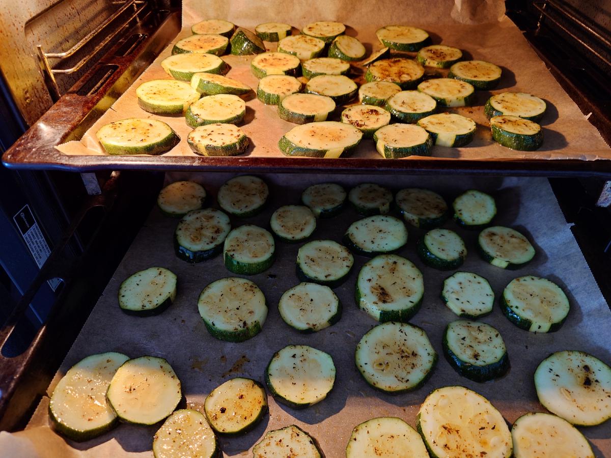 Two parchment-lined trays of rounds in the oven, single layer with gaps