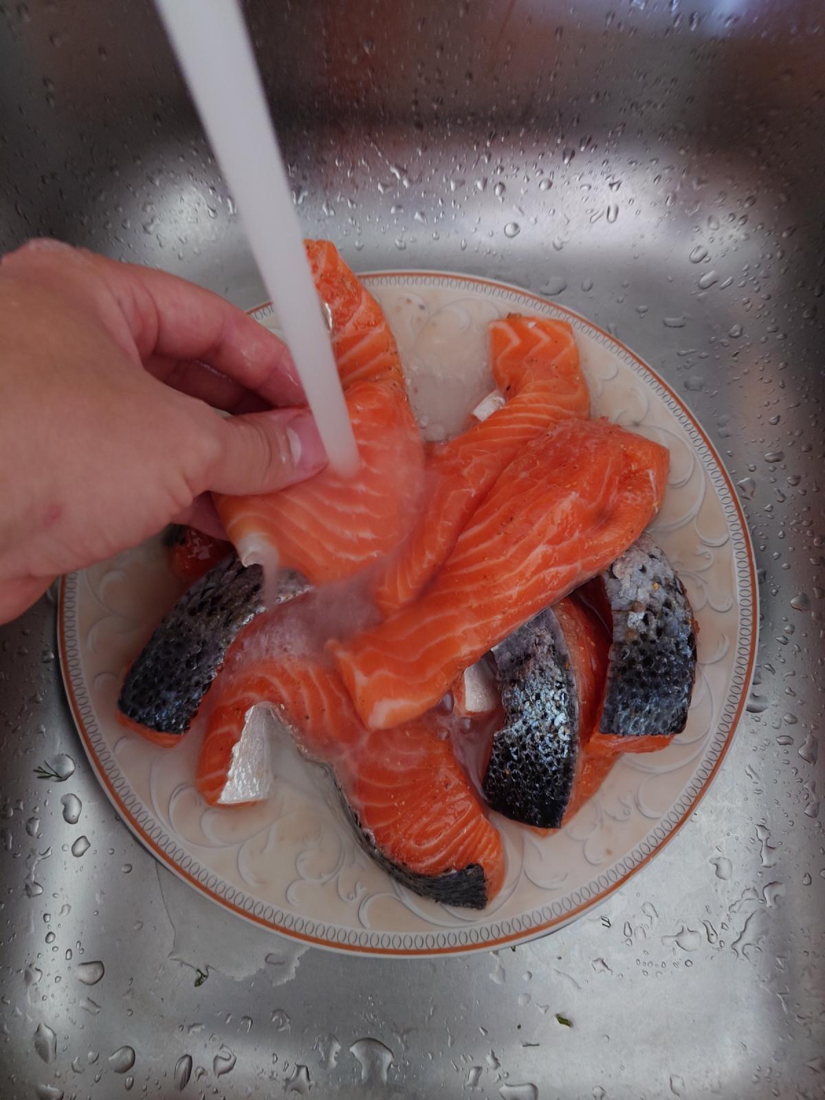 Cured salmon on a plate in the sink under running water