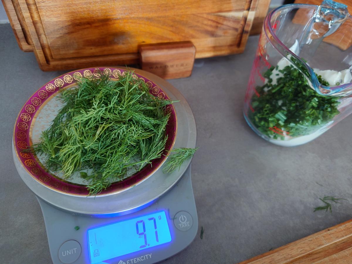 Picked dill on a plate on the scale reading 9.7 g