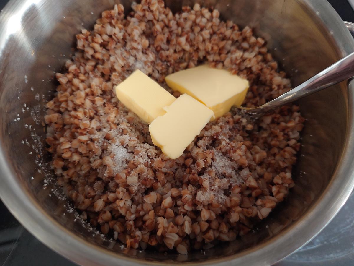 Three pieces of butter and salt on the cooked buckwheat in the pot