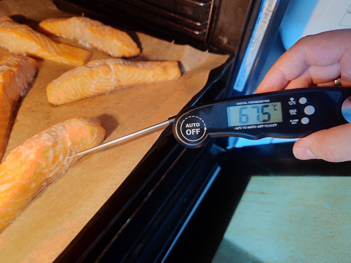A probe thermometer in a fillet reading 67.5 °C, tray still in the oven